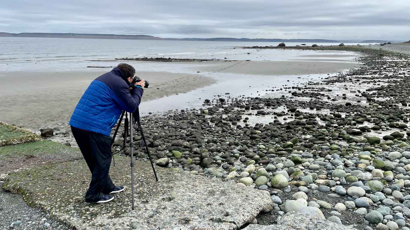 Picture of a photographer in the Pacific Northwest taking a picture of the beach